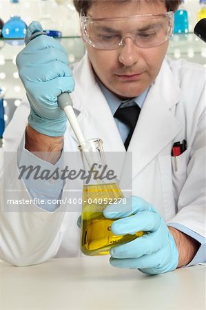 Scientist, chemist or pharmacist using a pipette and erlenmeyer flask in a laboratory.  Focus to pipette and flask.