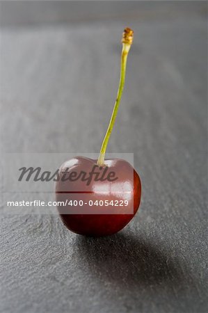 Single red cherry on a slate background