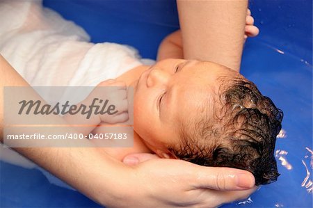 A baby girl in a bathtub at her mother