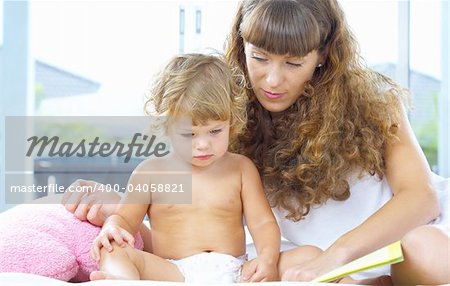 High key portrait  of young mother reading a book for her baby