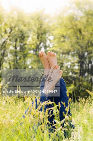 Couple lying in grass stretching their legs up. Copy space