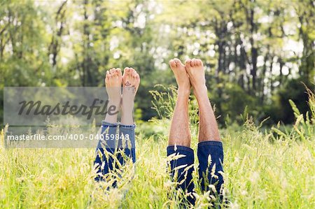 Couple lying in grass stretching their legs up