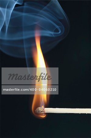 ignited match with blue smoke on black background