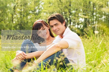 Couple lying in grass, smiling and hugging