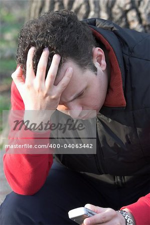 Anxious Man Holding a Mobile Phone in the park