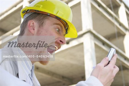 Crazy man with helmet talking on a cell phone in front of a building construction