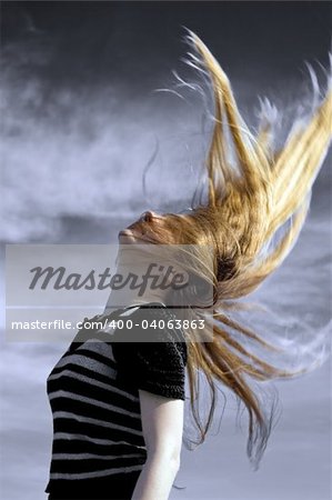 Sexy young woman with her long blond hair in the air