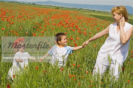 Woman and her children walking among poppies outdoors