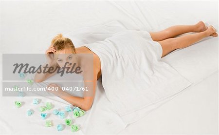 Beautiful young woman relaxing in spa surrounded by aromatherapy items