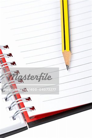 Pencil on a one notebook with soft shadow on white background. Shallow depth of field