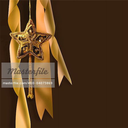 Gold christmas star with ribbons against dark background