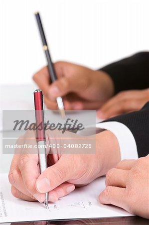 Two hand is signing the document, focused mainly on the front hand.
