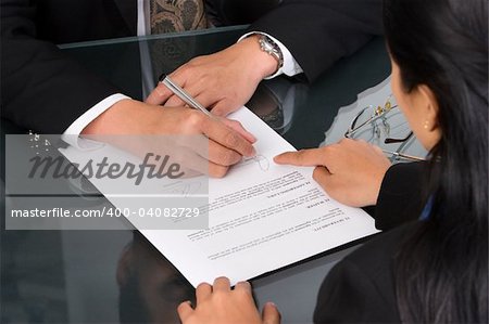 A business woman show the place on the document where the director should sign.