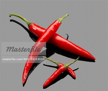 fresh red chili peppers over grey reflective surface