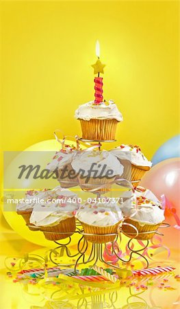 Lots of cupcakes on a muli-tiered stand against yellow background