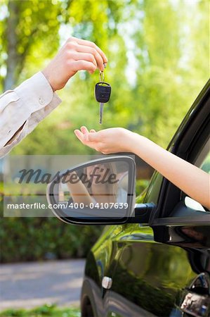 close up of female with arm outstretched taking car keys from man. Copy space