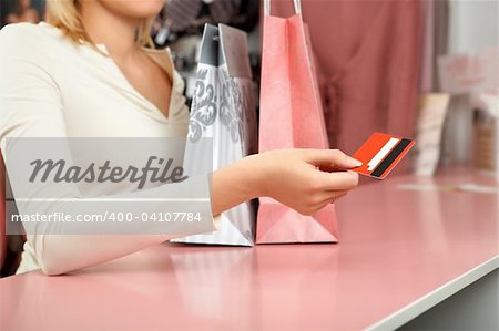 The girl holds a credit card over a counter in shop
