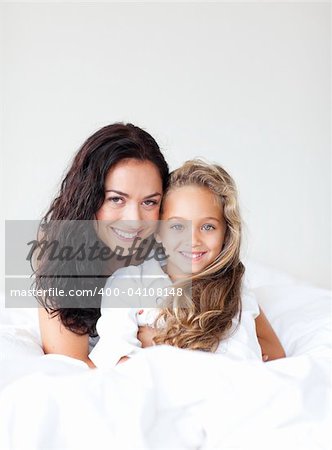 Junge Mutter und Tochter umarmt auf dem Bett
