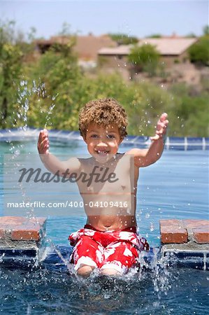 Cute young boy splashing in a swimming pool