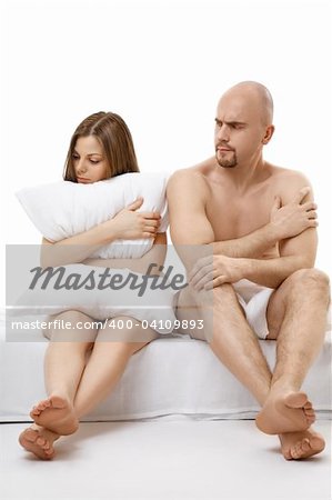 The man and the woman quarrel sitting in the bed, isolated