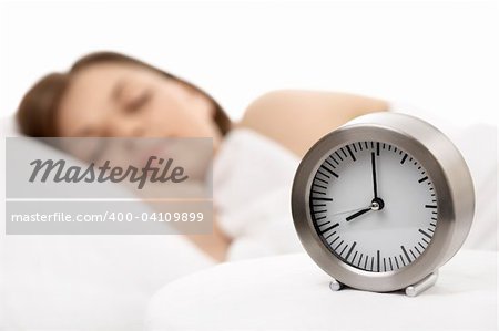 Alarm clock against the sleeping woman, horizontally