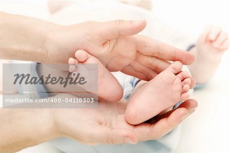 baby's feet in parent's hands over white