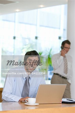 Confident smiling young business man working on laptop