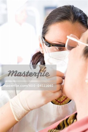 A young dentist buffing an old woman's teeth whit the turbine - part of a series.