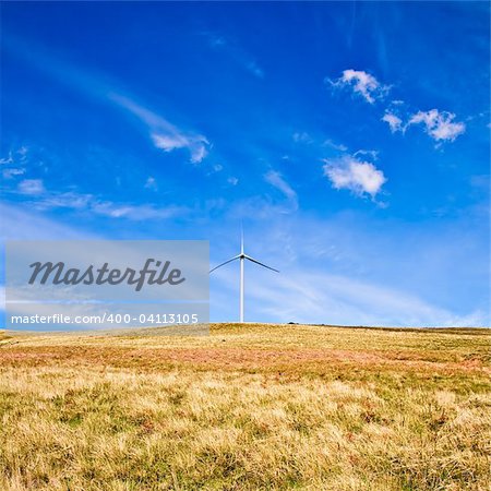 Wind tower on a field with blue sky.