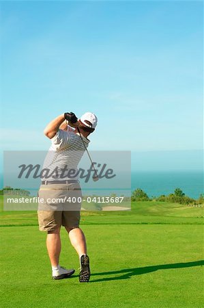 Young male golfer hitting the ball from the green on a beautiful summer day