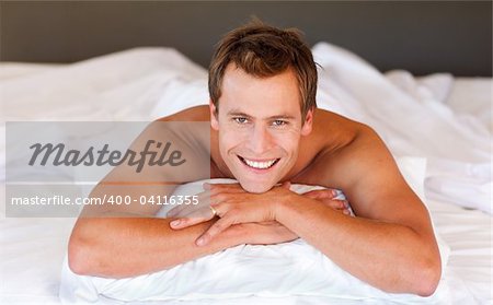 Attractive young man smiling on bed