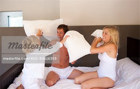 Family playing with pillows in bedroom