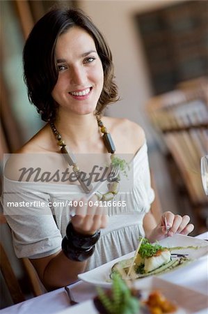 A young attractive woman eating a meal at a table outdoors