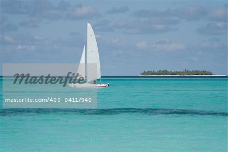 Sailing catamaran on the ocean. Island in the background