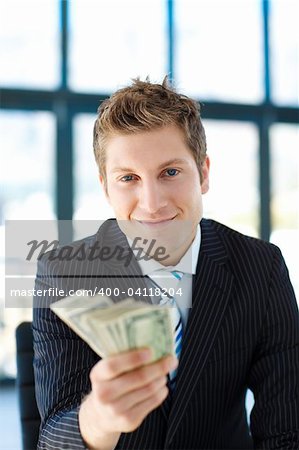Handsome junior businessman holding dollars and looking to the camera