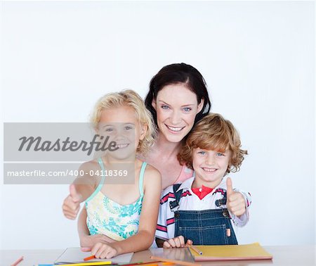 Happy children doing homework with their mother with thumbs up