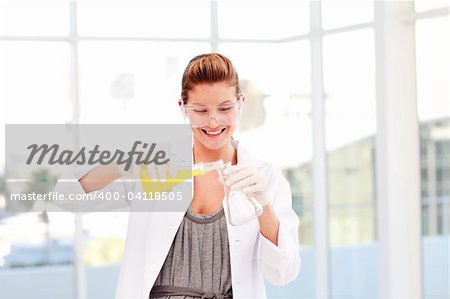 Smiling female scientist examinig a test-tube in a laboratory