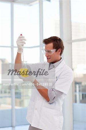 Young smiling scientist examining a chemical test-tube