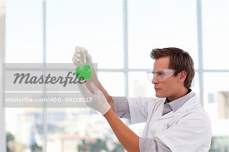 Young serious scientist examining a chemical test-tube with copy-space