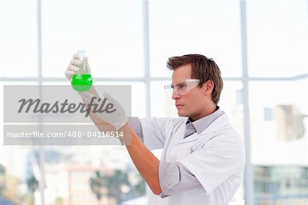 Young smiling scientist examining a chemical test-tube