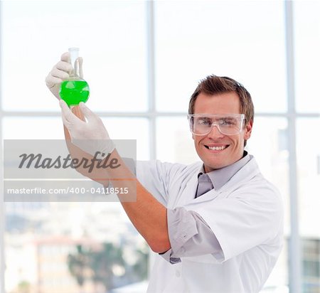 Scientist examining a test-tube in a laboratory smiling at the camera