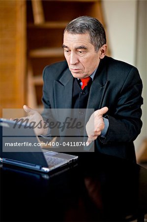 A businessman recoils from his laptop computer in horror.