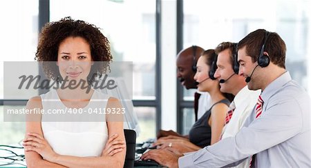 Attractive young businesswoman with folded arms in a call center