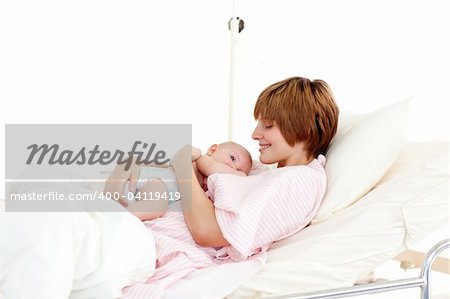 Smiling patient with newborn baby in bed in hospital