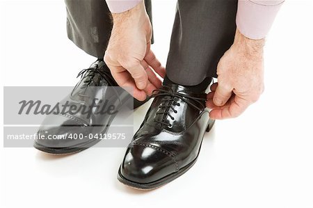 Man ties his shiney new black leather business shoes.  Isolated on white.