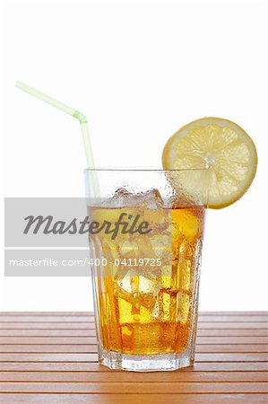 A glass of ice tea with lemon slice and straw on wooden background. Shallow depth of field