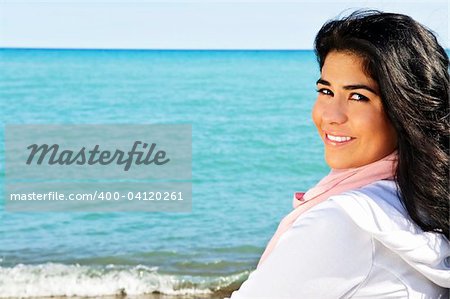 Portrait of beautiful smiling brunette girl at beach looking over her shoulder