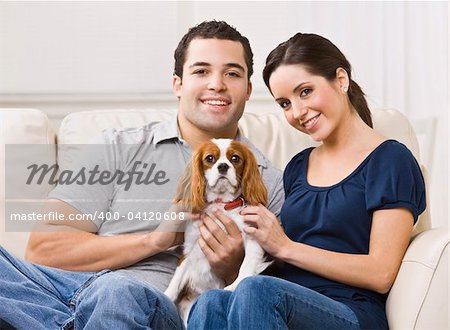 Attractive couple with their dog on their living room couch. horizontal