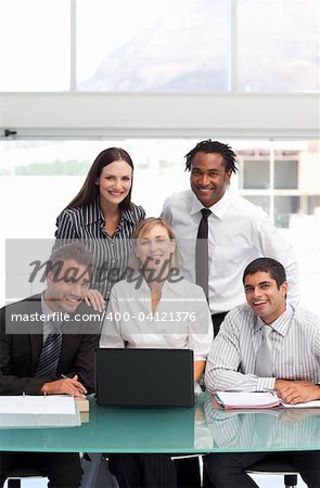 Smiling businessteam working together with a laptop in office