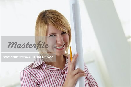portrait of young adult architect holding blueprint and smiling. Copy space
